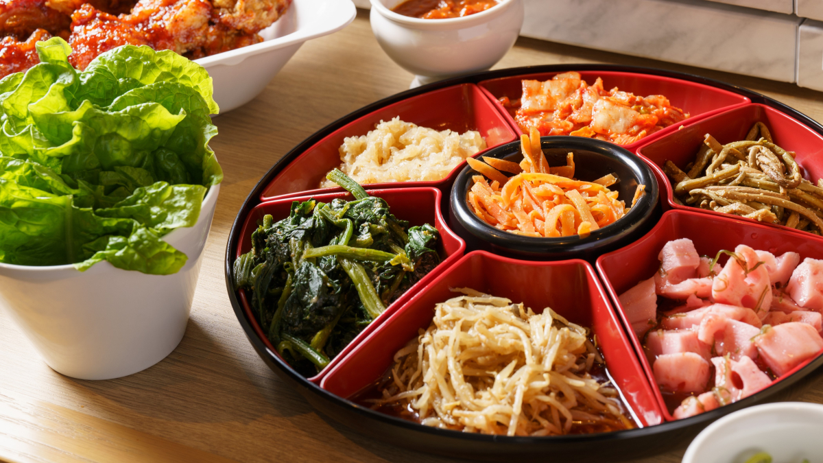 サンチュの葉と一緒に盛り付けられた韓国の盛り合わせ料理、様々な野菜のナムルが含まれている
