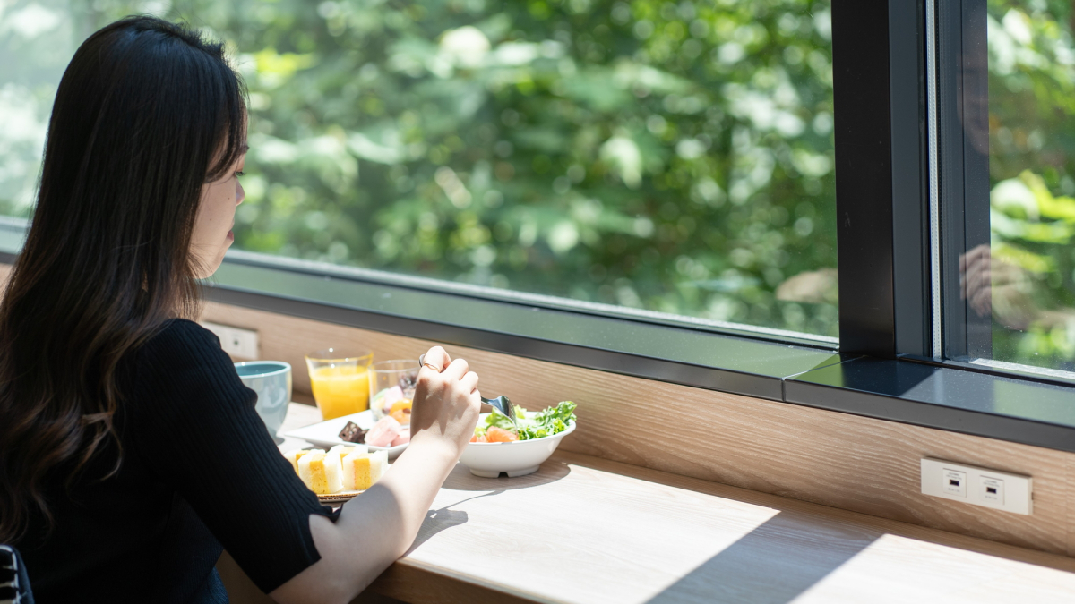 窓際のカウンター席で朝食を食べる女性
