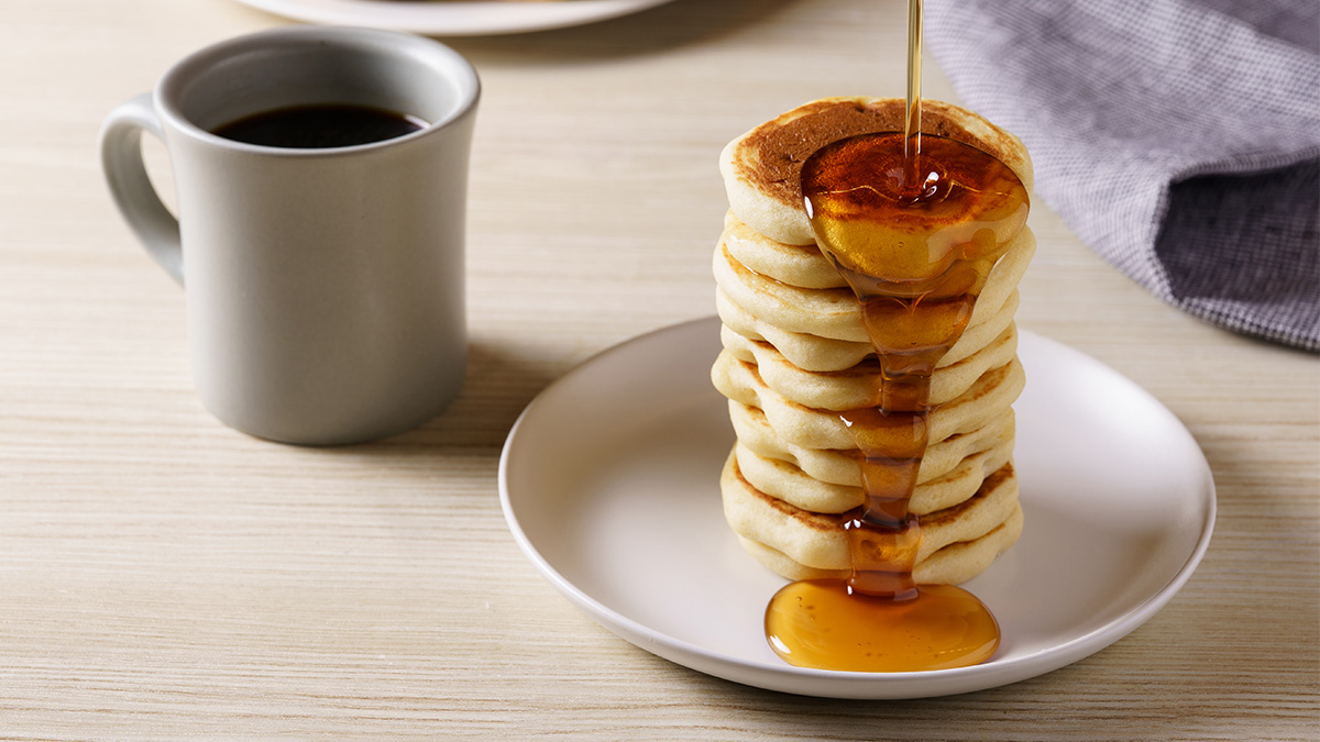 積み重ねたパンケーキにメープルシロップをかけている様子