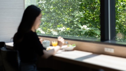 窓際のカウンター席で朝食を食べる女性